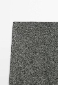 Gros plan d'un panneau en tissu tricot gris avec une couture horizontale près du bord supérieur sur un fond blanc.