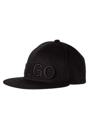 Casquette noire à visière plate avec broderie noire en relief formant le mot "HUGO" sur le panneau avant, présentée sur un fond blanc.