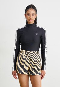 Zwarte lange mouwen top met witte strepen en hoge hals, gecombineerd met gele en zwarte gestreepte shorts. Glad stof met elastische tailleband.