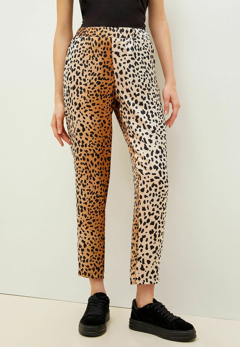 Pantalones con estampado de leopardo con un diseño dividido que presenta colores beige y marrón. Hechos de una tela suave, con una silueta ajustada y una longitud cropped.