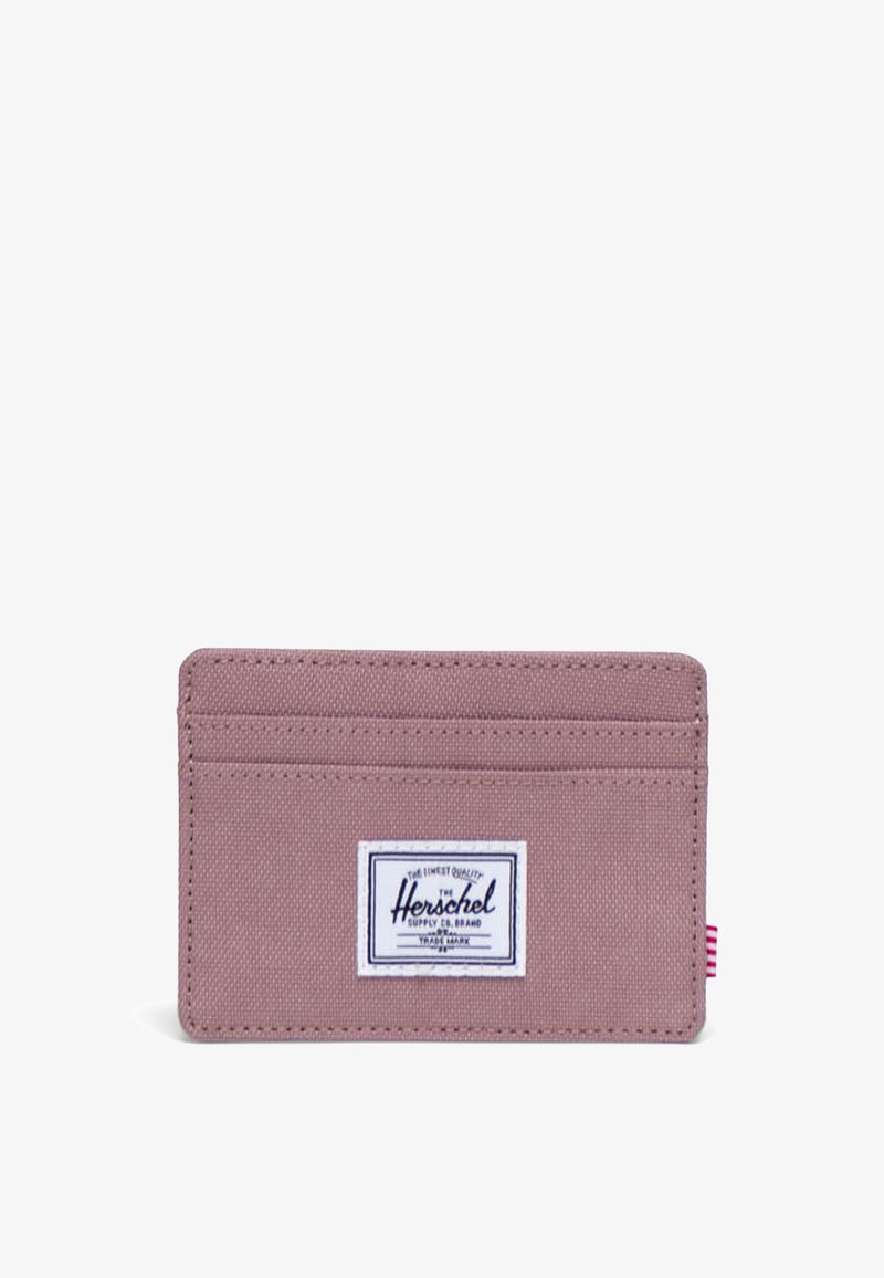 Portfel Herschel w tkaninie w kolorze mauve, posiada wiele przegródek na karty, naszywkę z logiem oraz kontrastowy paskowany akcent z boku.