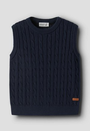 Gilet sans manches en maille bleu marine avec motif torsadé et bords côtelés, montrant une petite étiquette marron près de l'ourlet inférieur.