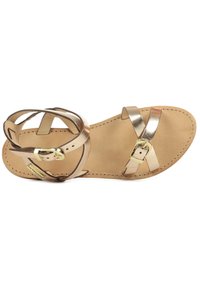 Sandale en cuir doré à brides croisées, semelle plate et une seule boucle. Texture lisse avec une semelle intérieure en cuir naturel.