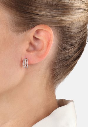 Orecchini a cerchio in argento con tre file parallele di piccoli cristalli trasparenti, caratterizzati da una finitura lucida e un sistema di chiusura sicuro.