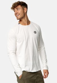 Weißes Langarm-T-Shirt mit Rundhalsausschnitt und schwarzem Logo auf der Brust. Es zeichnet sich durch eine glatte Textur und dezente Stickdetails aus.