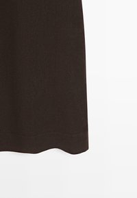 Saum eines schwarzen Stoffrocks mit subtilen Nahtdetails vor weißem Hintergrund, zeigt Textur und gerade geschnittenen Rand.