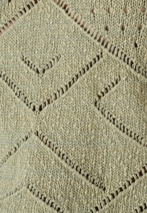 Tela tejida con patrones en forma de diamante y pequeñas perforaciones en hilo beige, mostrando textura y detalles de puntadas.