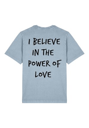 Lichtblauw katoen T-shirt met korte mouwen en een ronde hals. Bevat vetgedrukte zwarte tekst op de achterkant: "IK GLOOF IN DE KRAFT VAN LIEFDE."