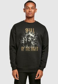 Sort sweatshirt med et grafisk design af et kranium og grene, med guld- og hvid tekst "SKULL OF THE NIGHT" i et fedt design.