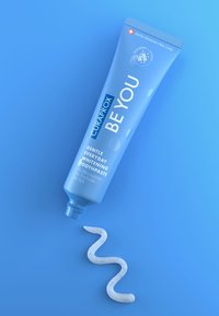Tubetto di dentifricio Curaprox BE YOU di colore azzurro chiaro, con testo bianco e tappo a vite. Sotto, una pasta bianca si presenta in una linea ondulata.
