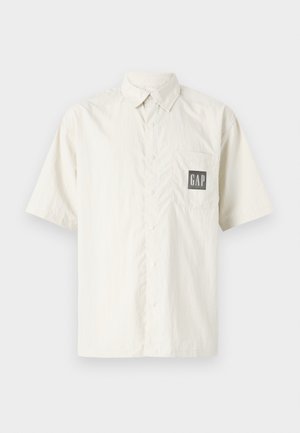 Short-sleeve cream shirt made from cotton, featuring a button-up front and a chest pocket with a contrasting black GAP logo.