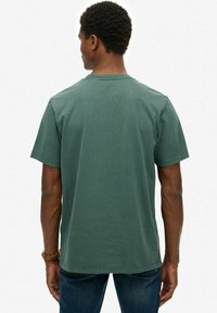 Ciemnozielona koszulka polo z krótkim rękawem, okrągłym dekoltem, wykonana z bawełny, charakteryzująca się gładką fakturą i luźnym krojem.