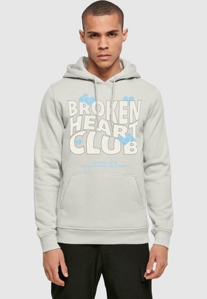 Light grey hoodie with a kangaroo pocket, featuring bold blue "BROKEN HEART CLUB" text and cloud accents, made from soft fleece material.