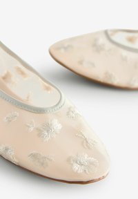 Ballet flats van zachtroze stof met witte bloemenborduursels, ronde neus en een contrasterende lichtgrijze bies langs de opening.