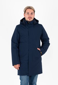 Giacca impermeabile blu navy con cappuccio, cerniera frontale e due tasche laterali. Presenta dettagli gialli sui polsini. Texture liscia.