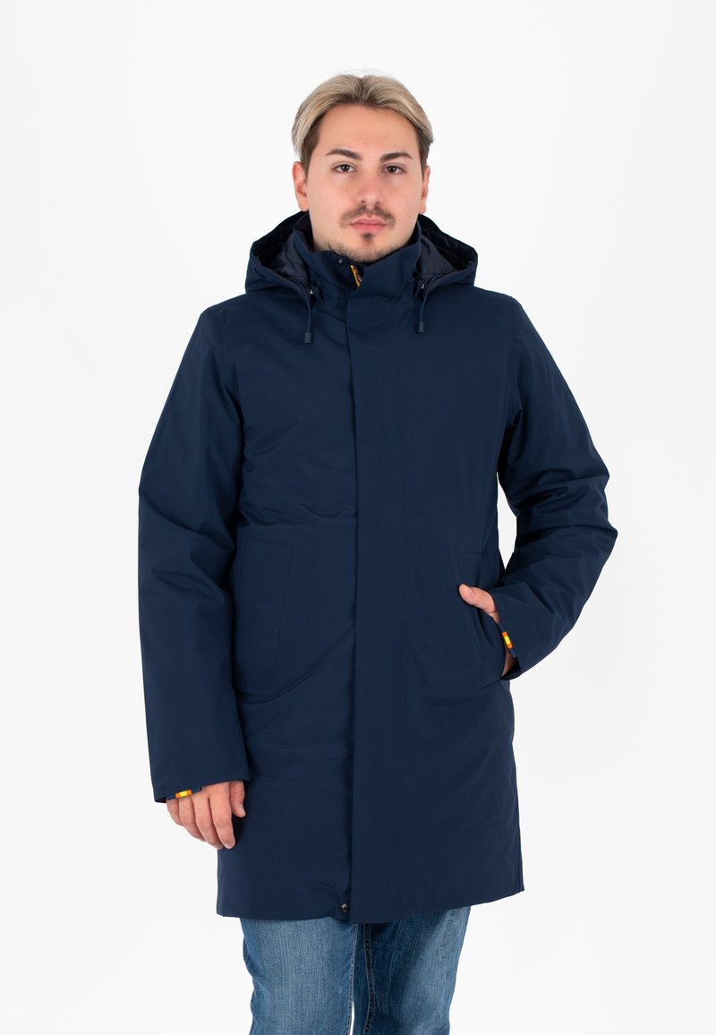 Giacca impermeabile blu navy con cappuccio, cerniera frontale e due tasche laterali. Presenta dettagli gialli sui polsini. Texture liscia.