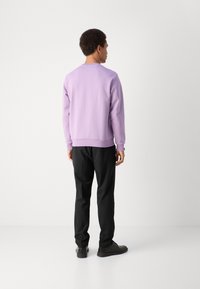 Ανοιχτό μωβ φούτερ με ριγέ μανσέτες και στρίφωμα, συνδυασμένο με μαύρα παντελόνια και μαύρα παπούτσια; λεία υφή, casual σχέδιο.