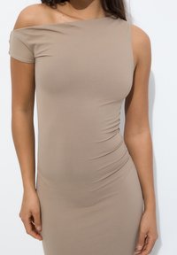 Robe beige à épaules dénudées en tissu extensible, ajustée avec une texture froncée sur le côté, surface lisse et manches courtes.