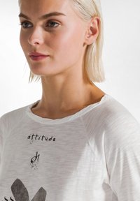 Witte, lichtgewicht, aangesloten t-shirt met een ronde halslijn, voorzien van zwarte bedrukte tekst en grafische ontwerpen op de voorkant. Zachte, gladde textuur.