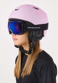 Roze skibril met een matte afwerking, zwarte accenten en een stevige kinband. Gecombineerd met donkere skibrillen met een reflecterende blauwe lens.
