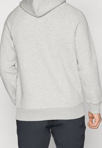 Haut à capuche gris avec un design classique, texture douce, poche kangourou sur le devant et finitions côtelées aux poignets et à l'ourlet. Vue arrière montrant la capuche et les coutures.