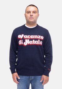 Maglione blu navy con il testo "Vacanze di Natale" in lettere pelose bianche e rosse. Collo a giro e polsini a coste con dettaglio laterale.
