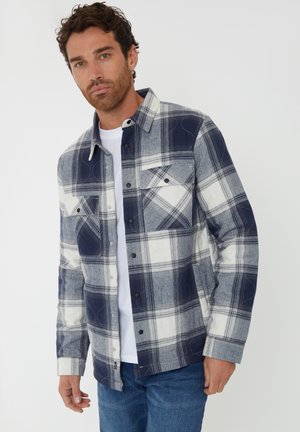 Camicia a scacchi con bottoni in navy, grigio e bianco, dotata di due tasche sul petto, colletto e vestibilità regolare. Realizzata in tessuto morbido e texturizzato.