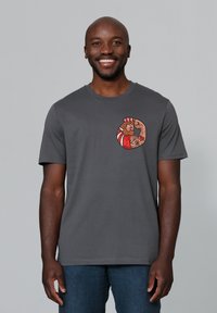 Graues T-Shirt mit kurzen Ärmeln, das ein farbenfrohes, kreisförmiges Grafikdesign mit detaillierten Illustrationen zeigt. Aus weichem Stoff gefertigt, bietet es eine lässige Passform.