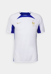 Camiseta de fútbol blanca de manga corta con detalles en azul, cuello redondo, logo de Nike en dorado y emblema nacional francés bordado.