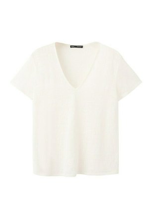 Bijela majica s kratkim rukavima i V-izrezom, s lagano opuštenim krojem i malom crnom oznakom unutar izreza na vratu.