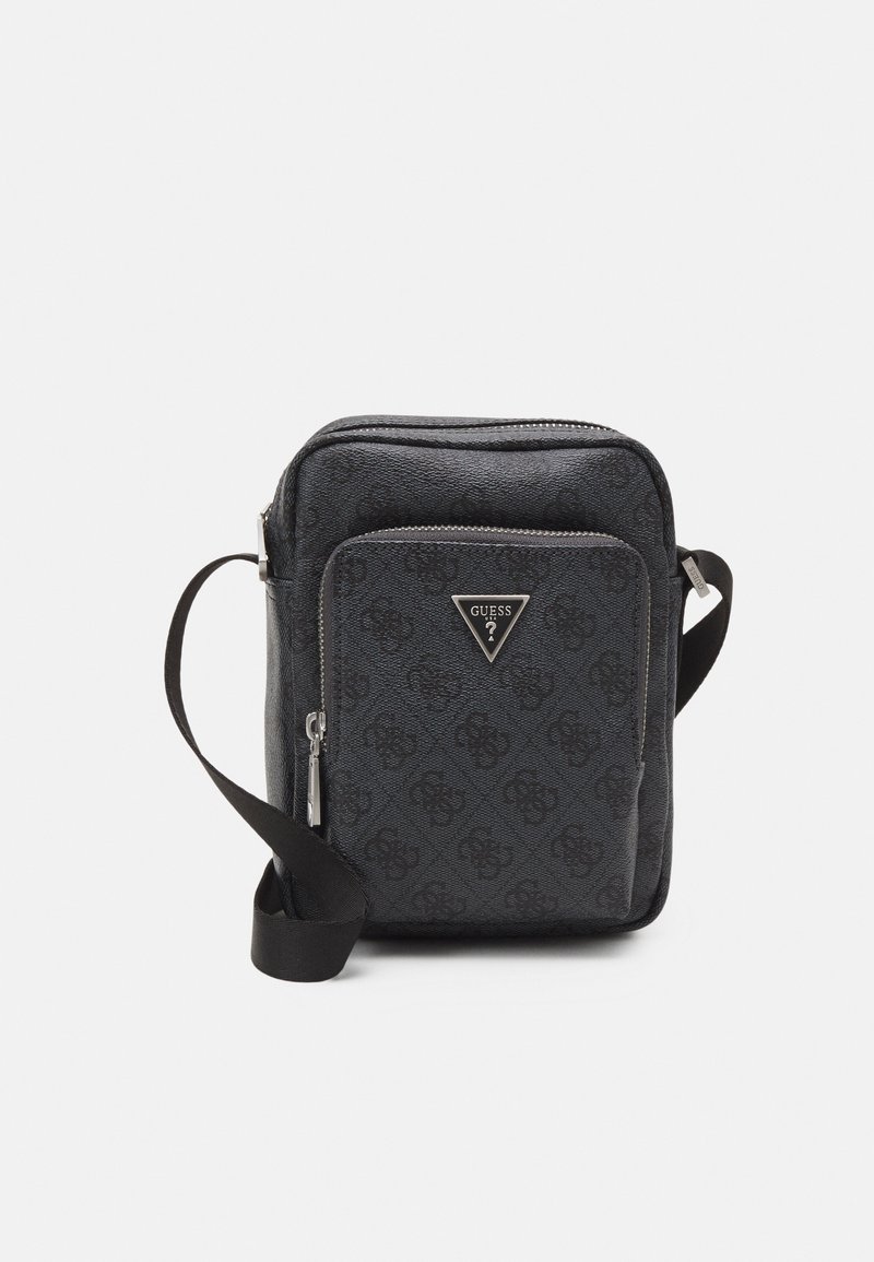 Bolsa transversal preta com material texturizado, apresentando um logótipo Guess proeminente, bolso frontal com fecho e strap regulável.