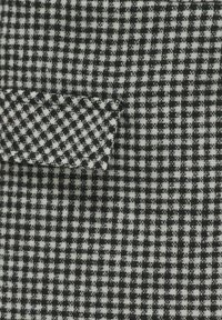 Svartvit rutig tyg med en liten ficka med en texturerad yta. Mönstret är konsekvent med en rutnätslayout.