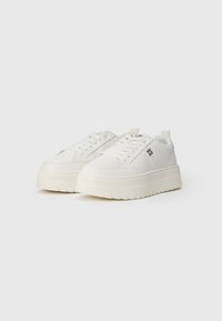 Witte sneakers met een gestructureerde platformzool, ronde neus en platte veters. Heeft subtiele branding aan de zijkant en een versterkte hielstrip.