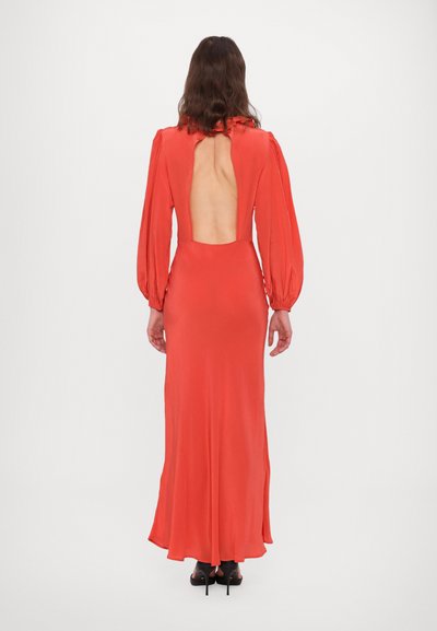 Ilga, glaudžiai aptempianti ryškiai koralinės spalvos suknelė su gilia iškirpte nugaroje, ilgomis pūstomis rankovėmis ir lygiu, minkštu audiniu.