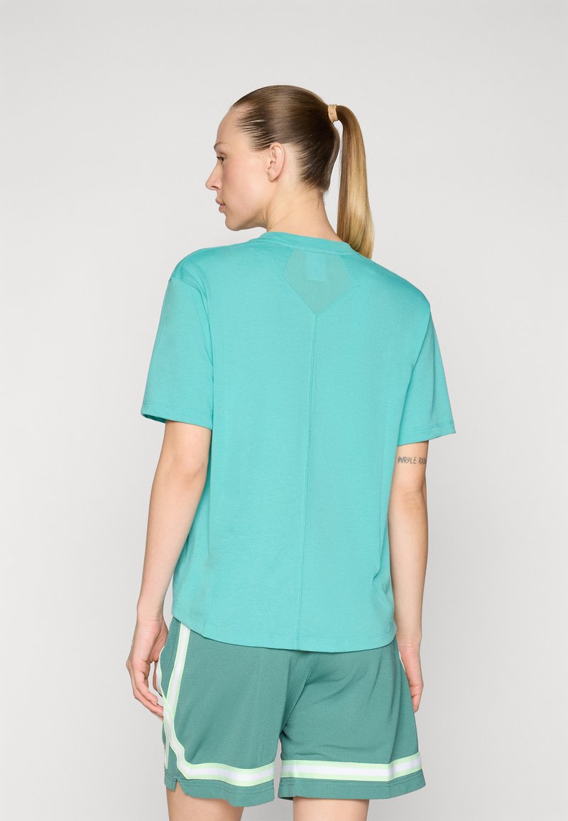 Türkiser T-Shirt mit kurzen Ärmeln, rundem Ausschnitt und einem Mesh-Rautendetail auf der Rückseite, kombiniert mit grünen Shorts mit weißen Streifen.