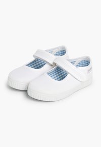 Scarpine Mary Jane bianche in tela con strap in Velcro, fodera a quadri blu, punta arrotondata e suola in gomma testurizzata.