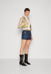 Fémes arany cropped dzseki, fehér felső, farmer mini szoknya és fekete bőr cowboy csizma. Kiegészítők között egy kis lime zöld kézitáska található.