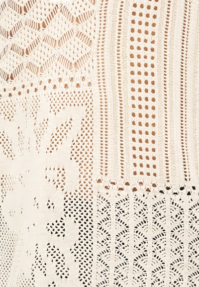 Υφασμα δαντέλας σε κρεμ χρώμα με διάφορα ανοιχτά σχέδια που περιλαμβάνουν λουλουδάτα, γεωμετρικά και ριγωτά μοτίβα.