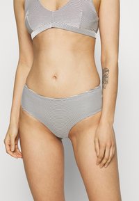 Bralette às riscas preto e branco e bottoms de bikini de cintura alta. Feito de um tecido suave; apresenta um design simples e limpo.