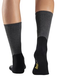 Graue, gerippte knielange Socken mit schwarzen verstärkten Fersen- und Zehenbereichen, die ein gelbes Logo auf der Sohle tragen.