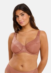 Soutien-gorge rose avec des bonnets supérieurs texturés et à motifs et des bords en dentelle. Bretelles larges et support par armature, fabriqué en tissu lisse et extensible.