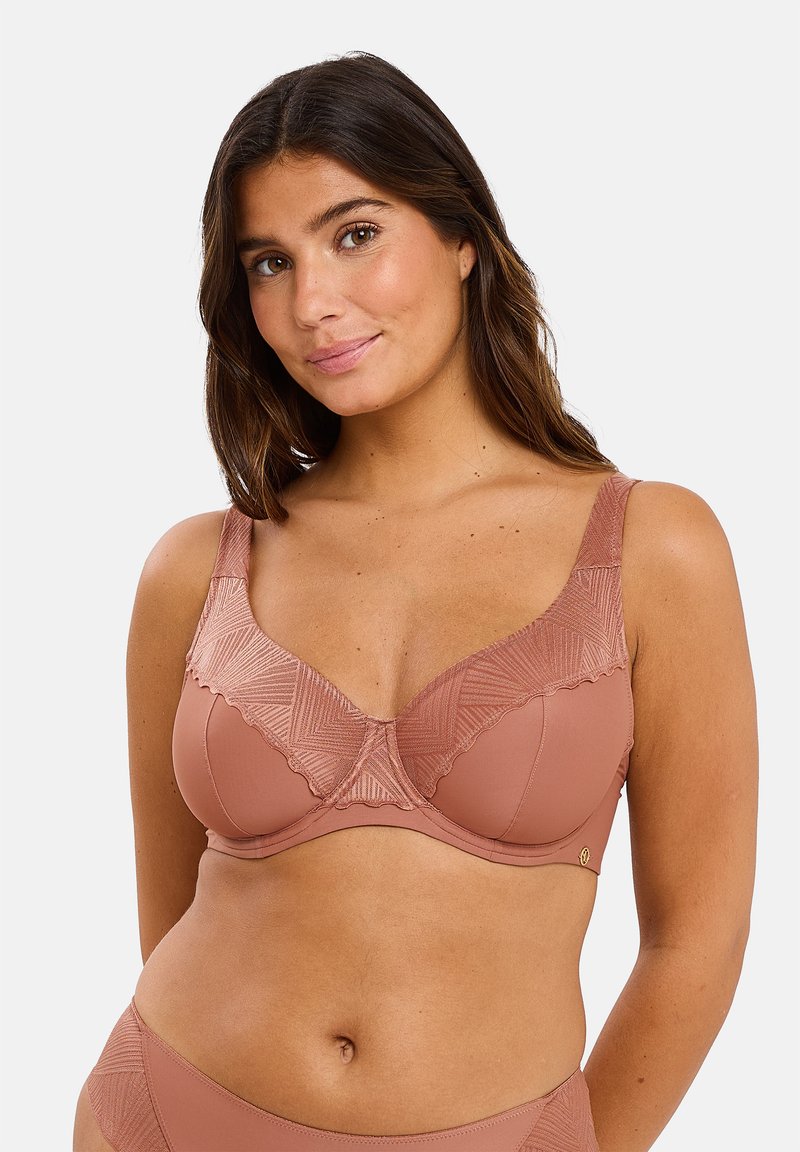 Soutien-gorge rose avec des bonnets supérieurs texturés et à motifs et des bords en dentelle. Bretelles larges et support par armature, fabriqué en tissu lisse et extensible.