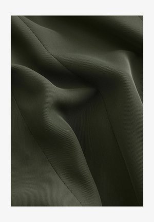 Tejido acanalado verde oscuro con una textura suave, que presenta pliegues y costuras suaves para una apariencia estructurada.