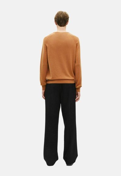 Pull en tricot marron avec ourlet côtelé, vu de l'arrière, associé à un pantalon noir ample. Design minimaliste, couleurs unies.