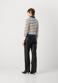 Maglione lavorato a maglia con righe bianche e nere, colletto blu, abbinato a pantaloni in pelle nera a vita alta e décolleté neri a punta.