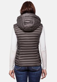 Mörkgrå vadderad väst med stor huva, med horisontellt quiltat mönster och figursydd design, bärs över en långärmad vit tröja.