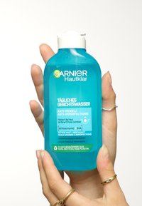 Garnier Hautklar gezichtsreiniger in een transparante turquoise fles met een witte pomp. Bevat anti-onzuiverheidstekst en een recyclebare label.