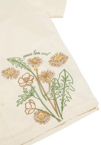 Camicia color crema con ricami floreali verde e marrone, con il testo "pace amore anima" sopra il design. Chiusura a bottoni sul davanti.