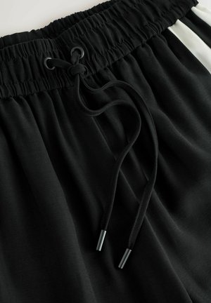 Schwarze Sportshorts mit elastischem Bund und Kordelzug, glatter Textur und kontrastierenden weißen Seitenstreifen.