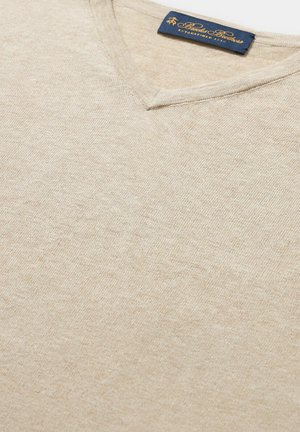 Beiger V-Ausschnitt-Pullover aus weichem, glatten Stoff. Verfügt über eine dezente Textur und ein marineblaues Etikett am Hals mit Markendetails.